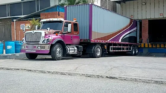 Tractomula con contenedor en el muelle de cargue de una bodega